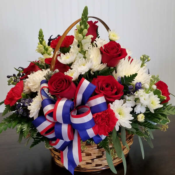 Basket arrangement of red roses and white daisies with a red-white-blue ribbon
