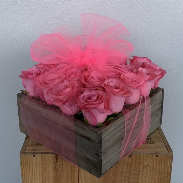 Pink roses arranged in a wooden box with sheer pink tulle