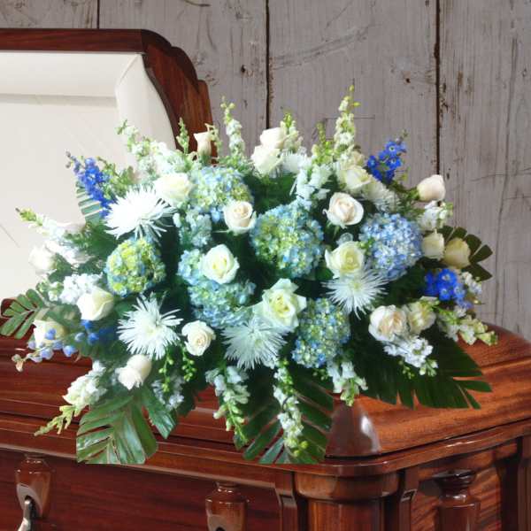 White and blue floral spray on a casket