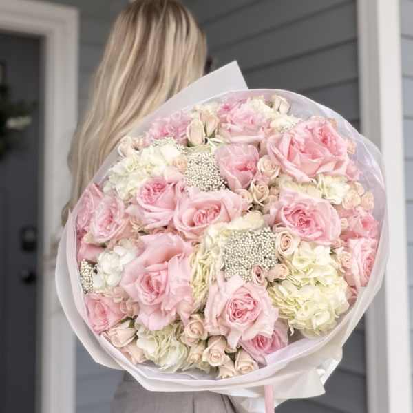 Large bouquet of pink and white roses wrapped in pale paper
