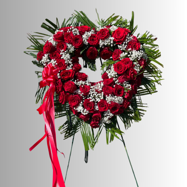 Heart-shaped red rose wreath with baby's breath and a pink ribbon