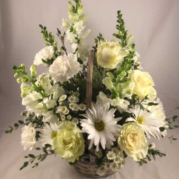 White and pale yellow flowers in a wicker basket arrangement