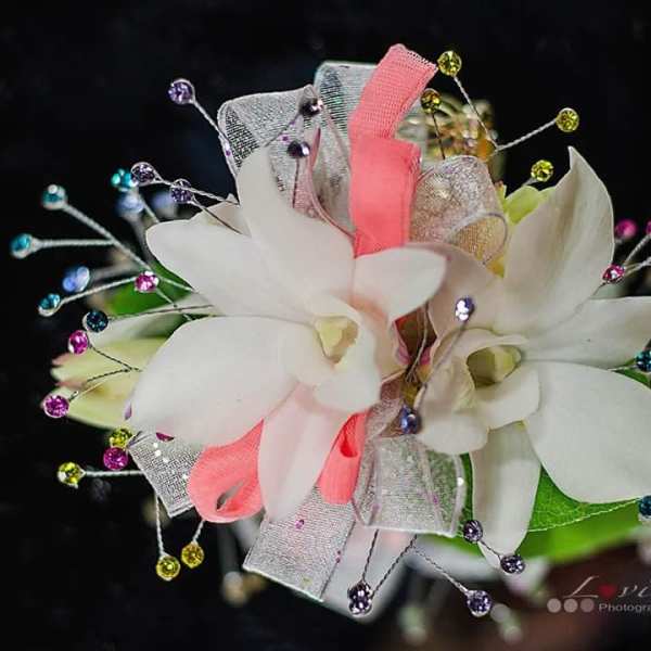 White orchid corsage with pink and silver ribbon and jeweled picks