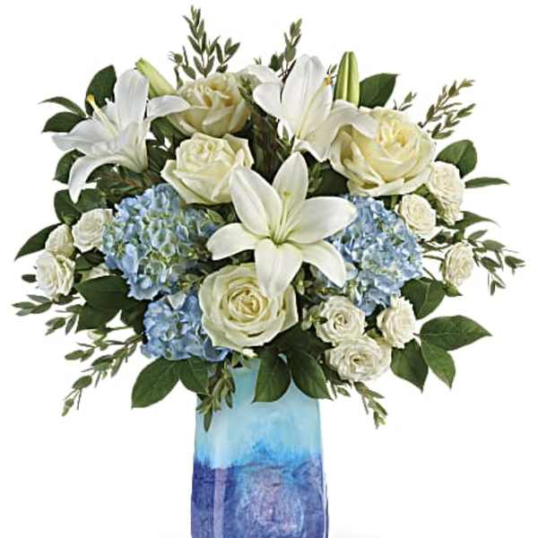 White lilies and roses with blue hydrangeas in a blue glass vase