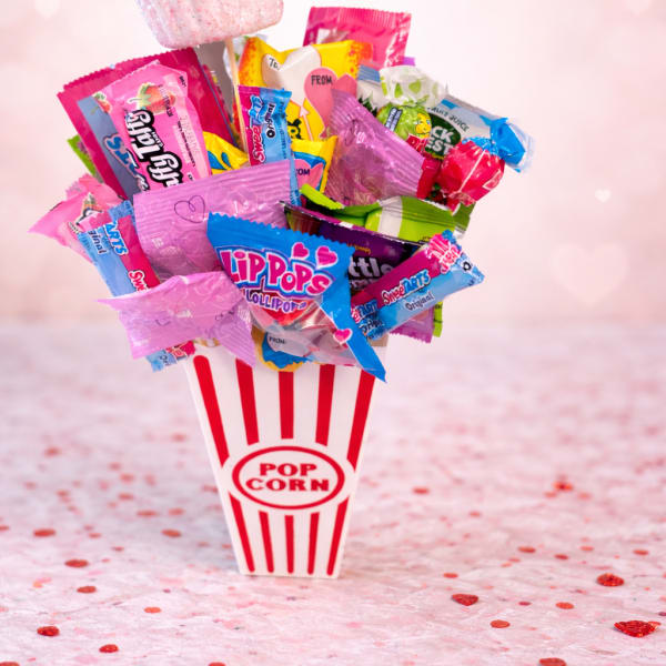 Candy bouquet in a popcorn container with a pink heart topper
