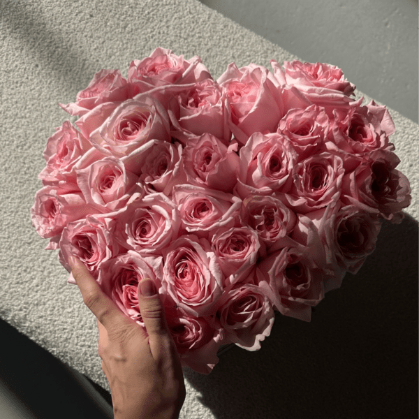 Heart-shaped bouquet of pink roses held in hand