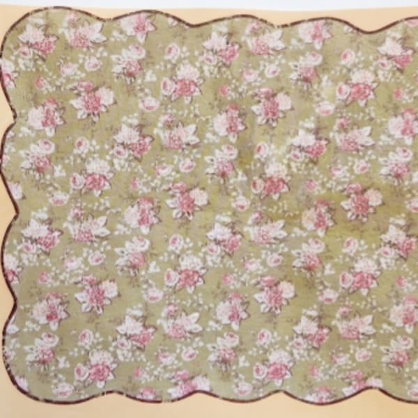 Floral-patterned scalloped fabric in pink and white on a green background