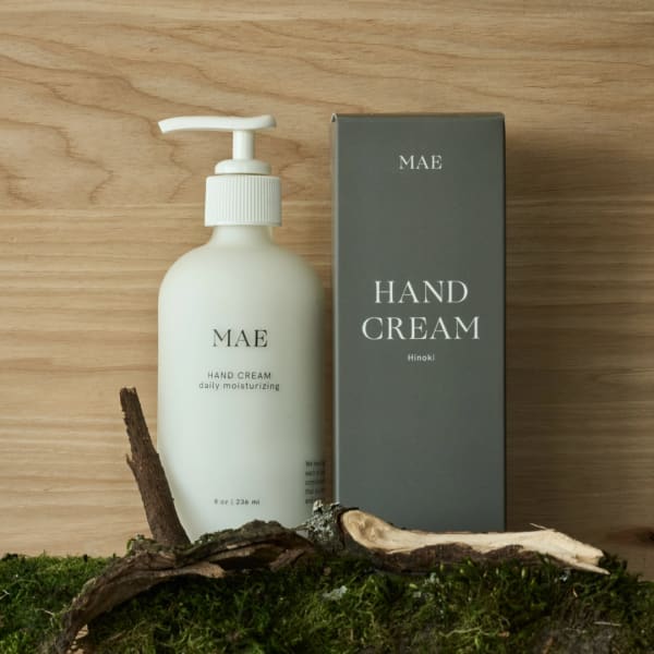 Hand cream bottle beside its box on a wood surface with moss and bark
