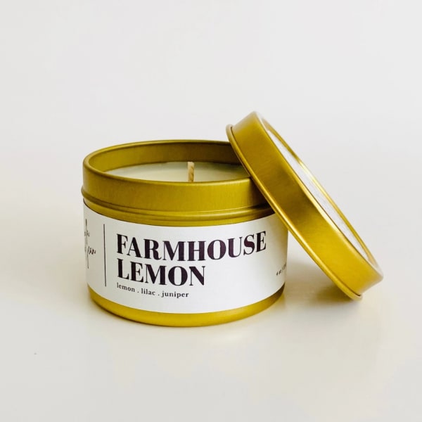 Gold tin candle labeled Farmhouse Lemon with lid beside it