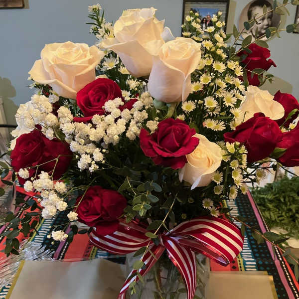 Bouquet of red and white roses in a glass vase with a striped ribbon