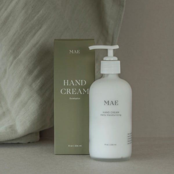 Bottle of hand cream beside its olive-green box