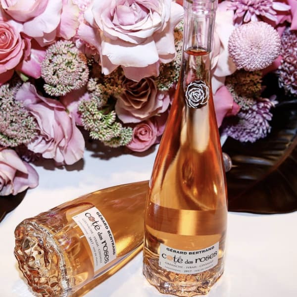 Pink roses with a rosé wine bottle and glass on a table