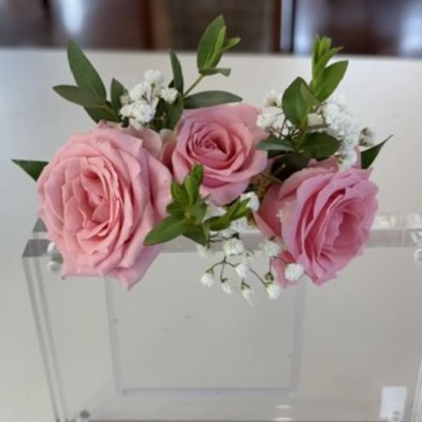 Pink roses with white filler flowers in a clear acrylic box