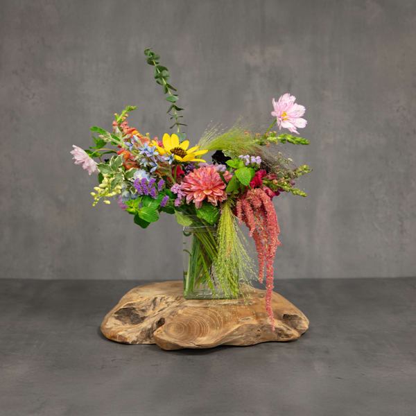 Mixed bouquet in a clear glass vase on a wooden slab