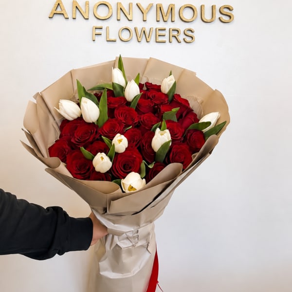 Bouquet of red roses and white tulips wrapped in tan paper