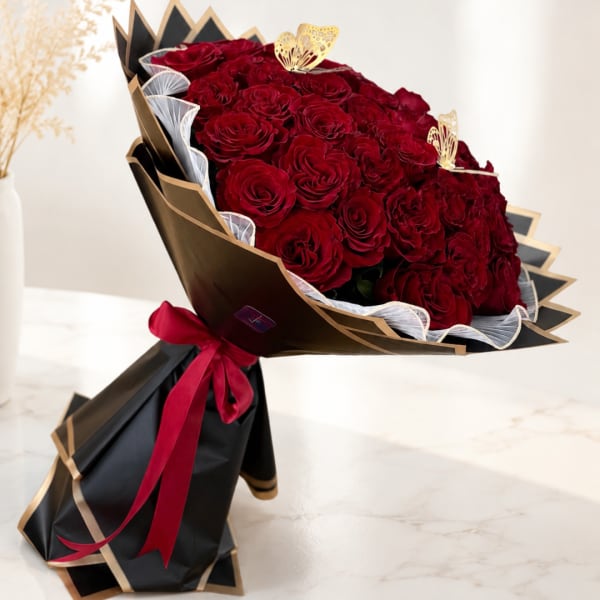 Bouquet of red roses wrapped in black and gold paper with a red ribbon