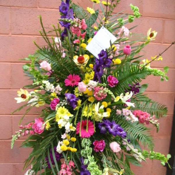 Tall standing floral spray with mixed bright flowers and greenery