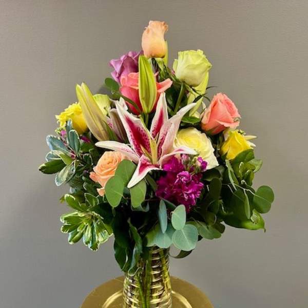 Mixed bouquet of roses and lilies in a gold vase