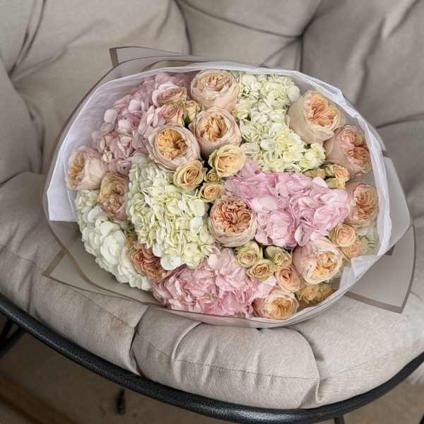 Bouquet of pastel roses and hydrangeas wrapped in white paper