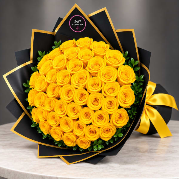 Bouquet of yellow roses wrapped in black paper with gold trim and a yellow ribbon