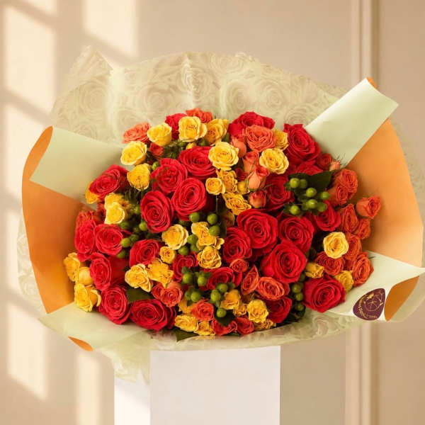 Bouquet of red, yellow, and orange roses wrapped in cream and orange paper