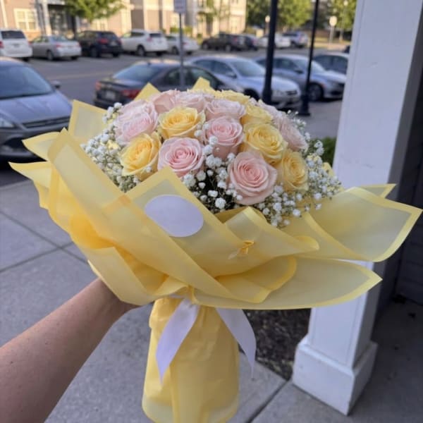Bouquet of pale pink and yellow roses wrapped in yellow paper