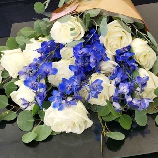 Bouquet of white roses and bright blue orchids wrapped in gold paper