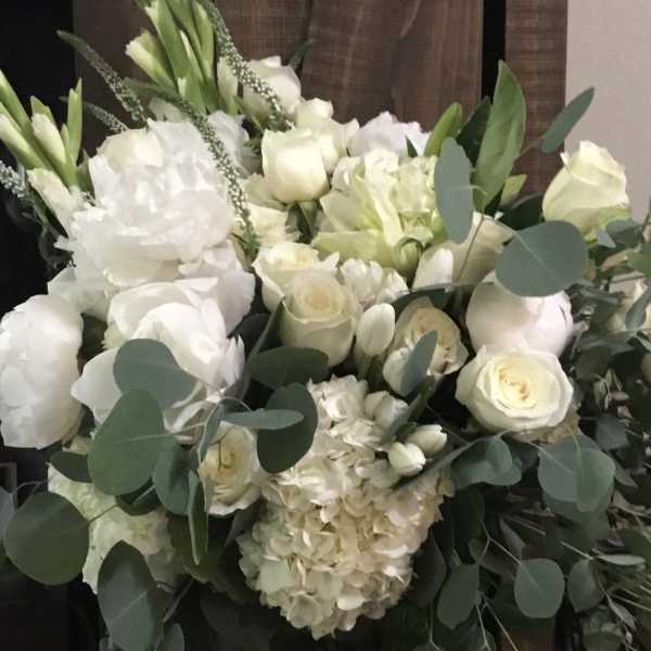White floral arrangement with roses, hydrangeas, and greenery in a vase
