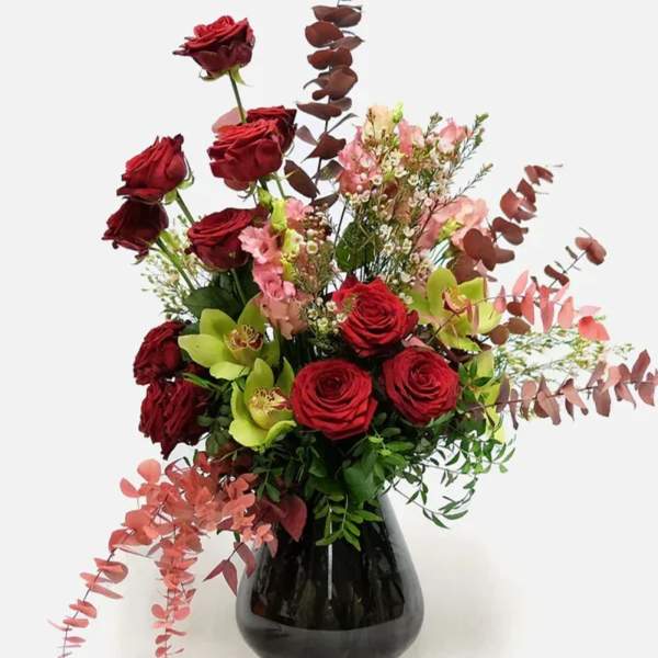 Red roses and pink flowers in a black vase