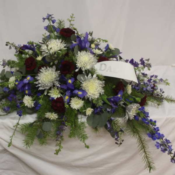 Casket spray with blue, white, and burgundy flowers