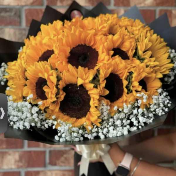 Bouquet of orange sunflowers with white baby's breath in black wrap
