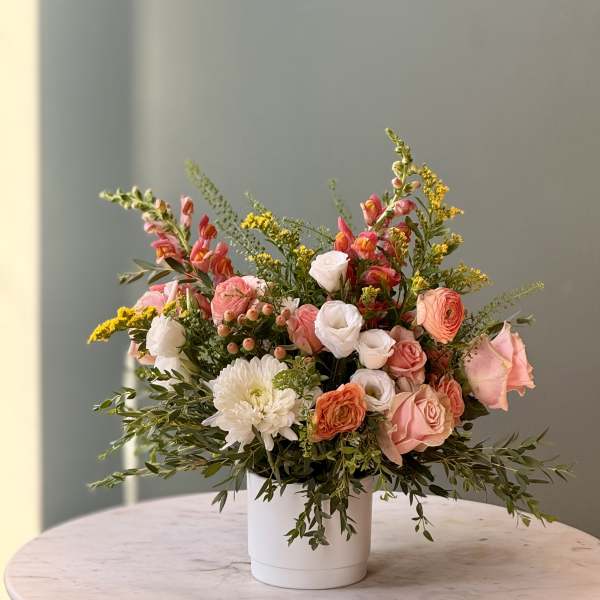 Mixed pink and white flower arrangement in a white vase