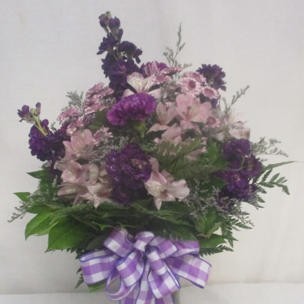 Purple and pink mixed bouquet in a glass vase with a checkered ribbon