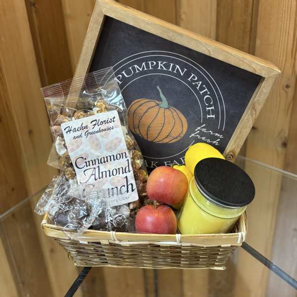 Basket of apples, candy, and a candle with a pumpkin patch sign