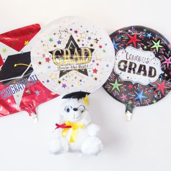 Three graduation balloons with a small teddy bear