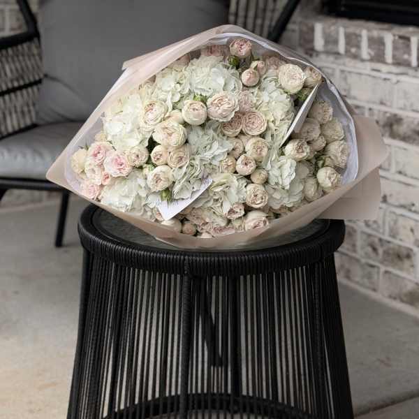 Large bouquet of pale pink and white roses wrapped in blush paper