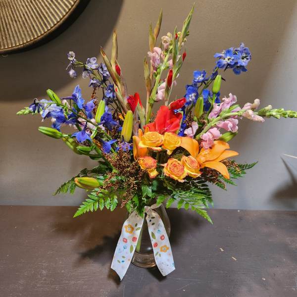 Colorful mixed bouquet in a glass vase with a patterned ribbon