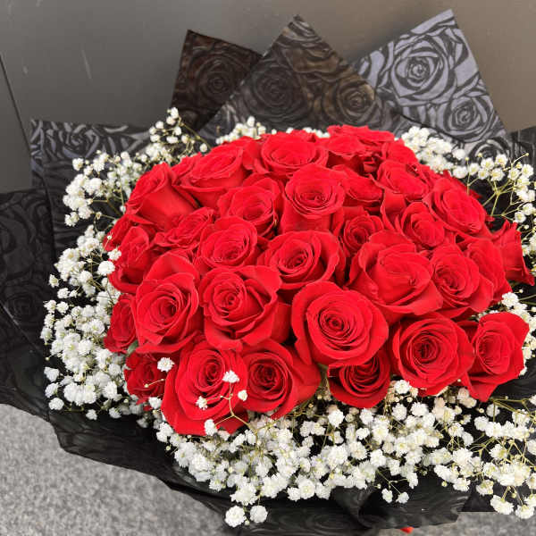 Bouquet of red roses with white baby's breath in black wrap