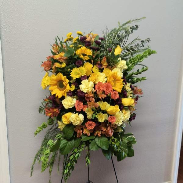 Large standing floral spray with yellow, peach, and purple blooms on an easel