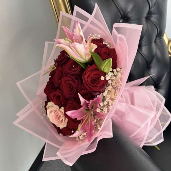 Bouquet of red roses and pink lilies wrapped in pink paper