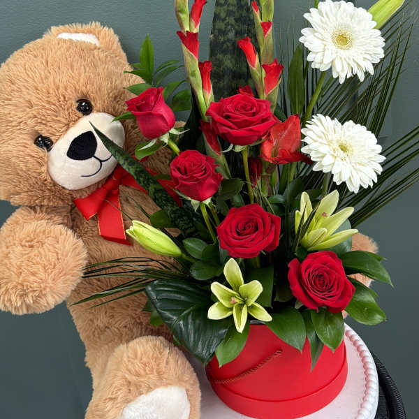 Red roses and white lilies in a red box with a teddy bear
