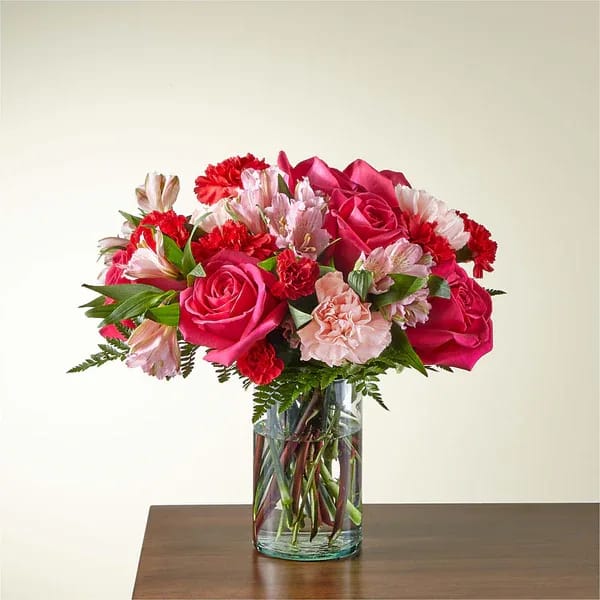 Bouquet of pink roses and mixed flowers in a clear glass vase