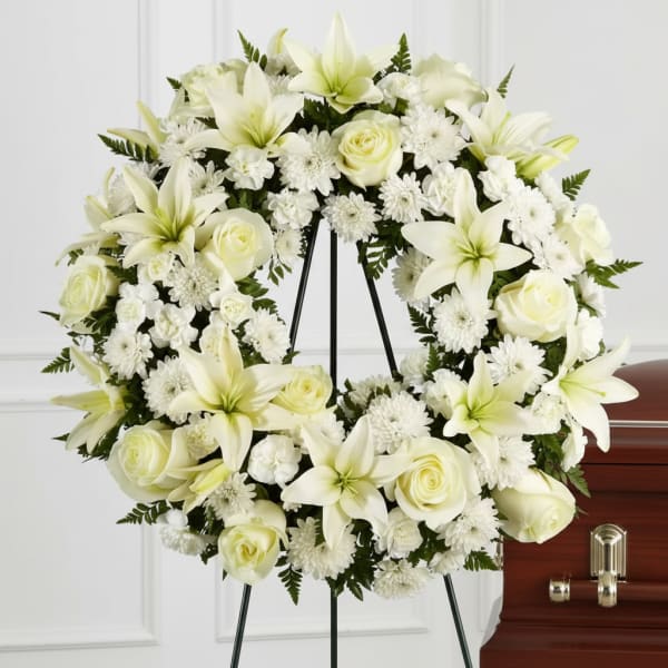 White floral wreath on a stand beside a casket