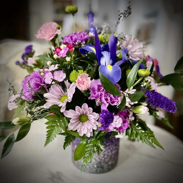 Mixed bouquet of purple, pink, and white flowers in a glittery vase