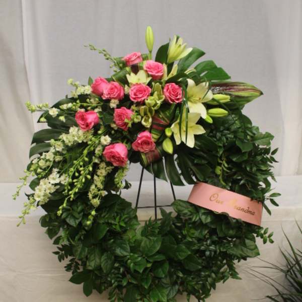 Pink roses and white lilies arranged in a large standing wreath