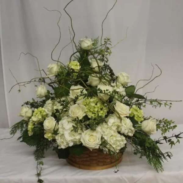 White rose and hydrangea arrangement in a low basket with curly branches