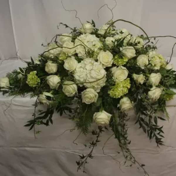 White rose and hydrangea floral arrangement with trailing greenery