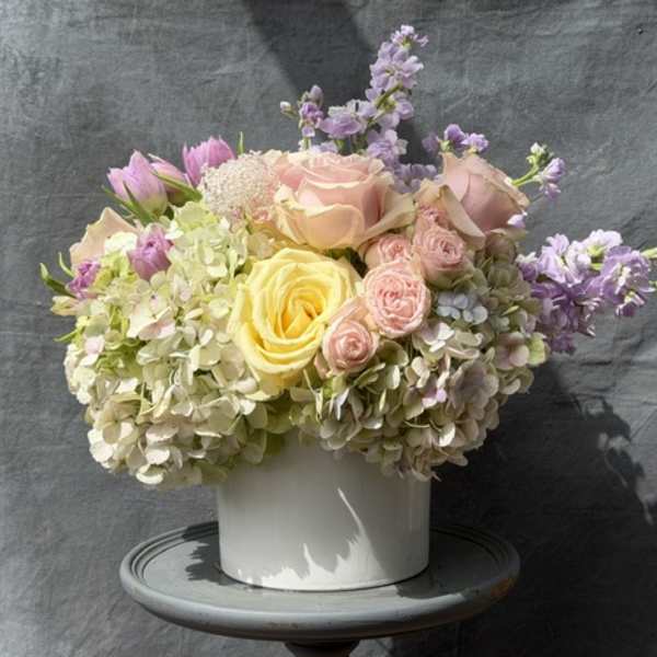 Pastel bouquet of roses, hydrangeas, and lavender flowers in a white vase