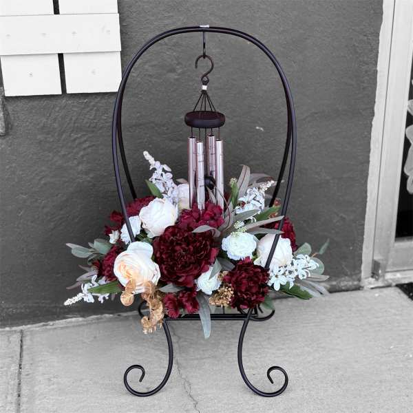 Floral arrangement on a black metal stand with hanging wind chimes