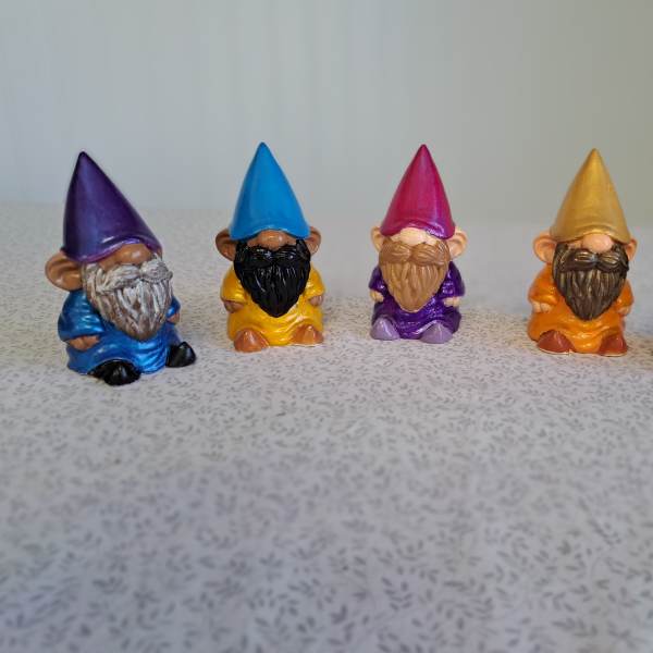 Five small colorful gnome figurines lined up on a tabletop